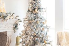 13 a snowy Christmas tree with gold and silver ornaments and a snowflake on top looks glam
