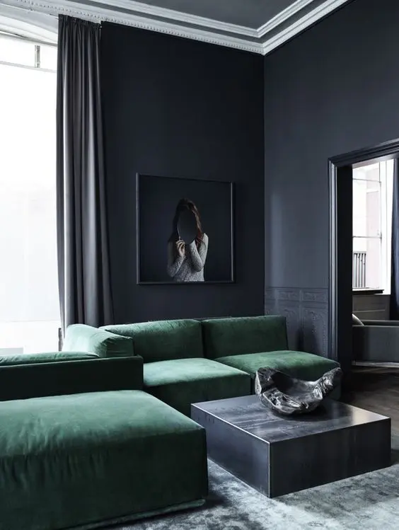 a moody minimalist space done around an emerald croner sofa and a grey coffee table