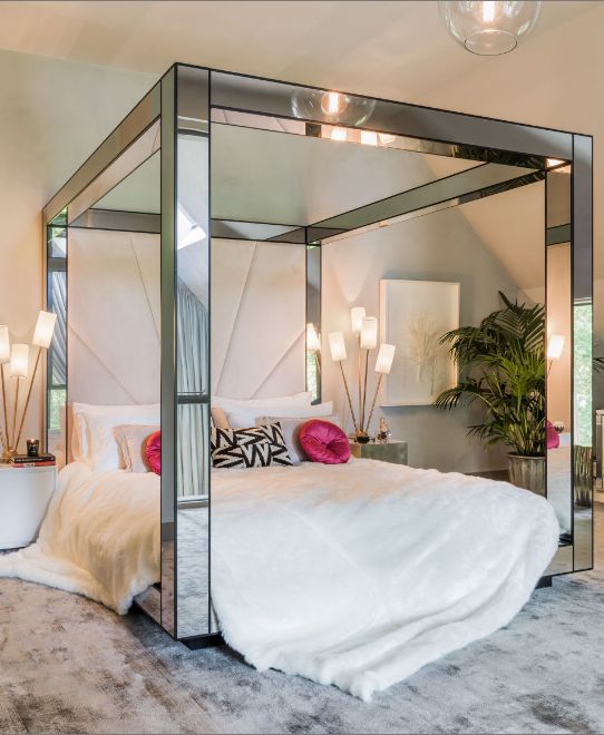 pink velvet pillows, a creamy faux fur blanket and a mirrored bed frame for an edgy look