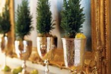 15 a mantel display with little evergreen trees in gold goblets and small apples