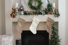 15 neutral stockings, an evergreen garland with lights, a wreath and some candles for pretty styling with a rustic feel