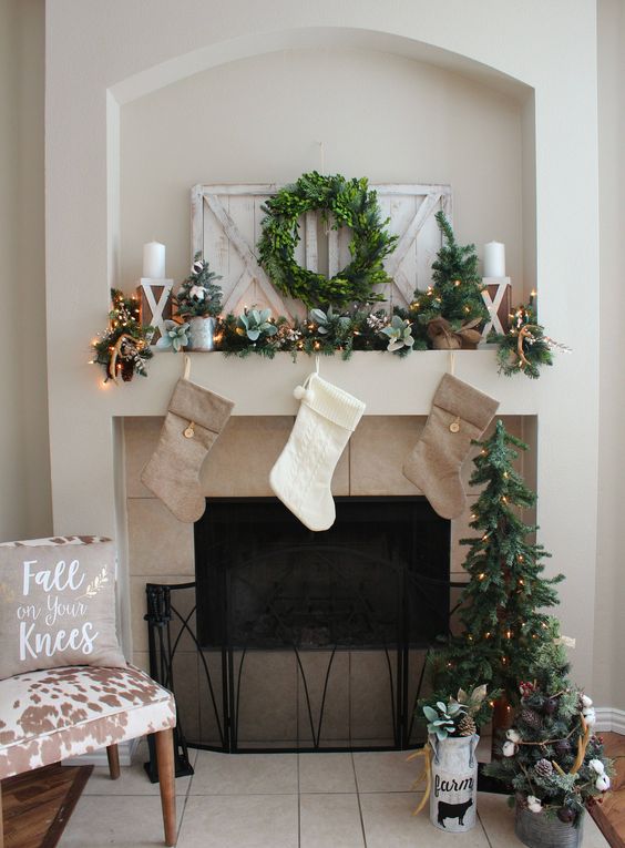 neutral stockings, an evergreen garland with lights, a wreath and some candles for pretty styling with a rustic feel