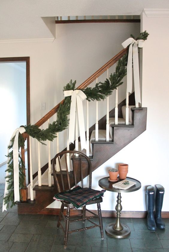 a lush evergreen garland with chic creamy ribbon bows to decorate the staircase