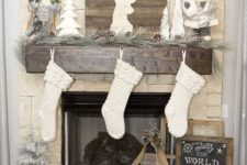 16 a pine garland with snowy pinecones, a pallet deer sign, Santa Claus dolls and white stockings