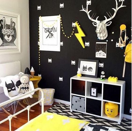 A black wall with a Batman print is made vivacious with yellow touches and artworks