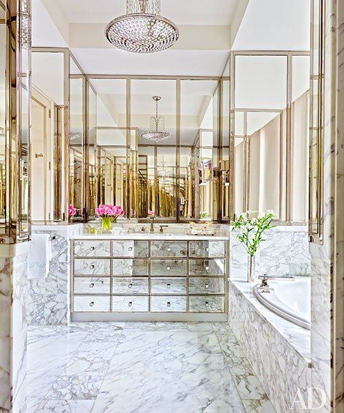 a built-in mirrored vanity with many drawers and marble and brass all over for a glam feel