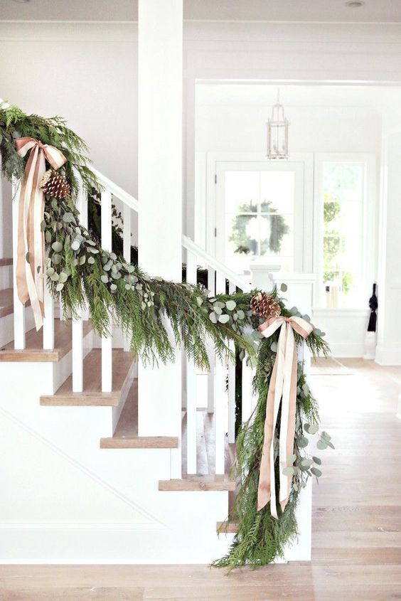 a lush evergreen garland with eucalyptus, pinecones and striped ribbon bows to decorate the stairs