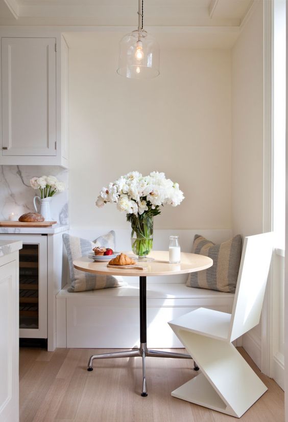 a tiny breakfast nook with a built-in bench, a round table and a geometric chair