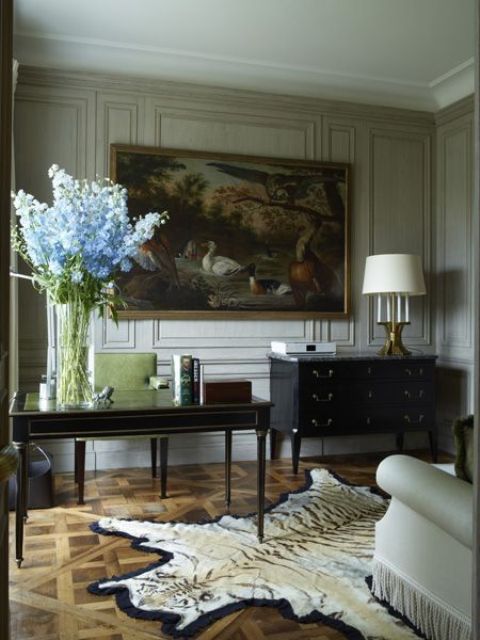 A vintage inspired home office with paneled walls and a gorgeous painting
