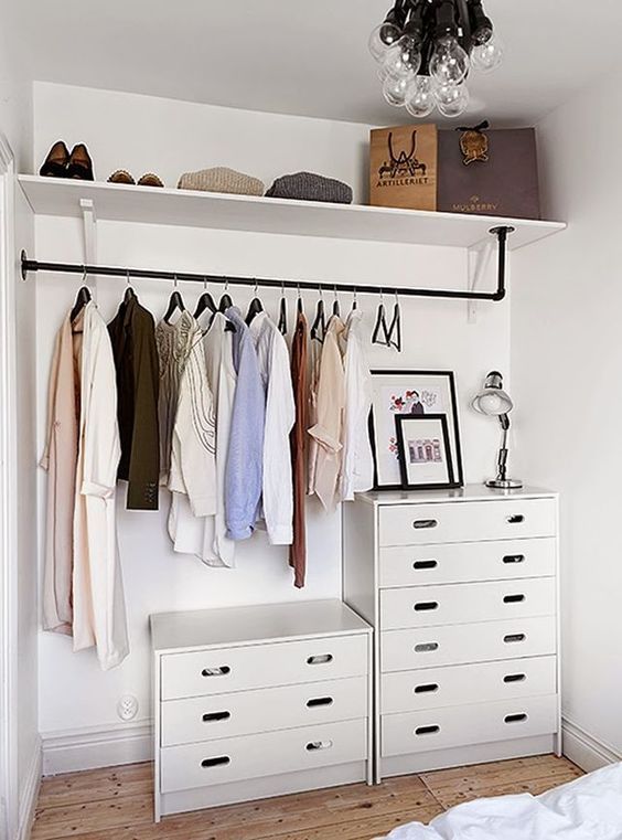 a makeshift closet with chests of drawers and open shelving in the bedroom