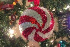19 a red and white sequin Christmas ornament reminding of a peppermint