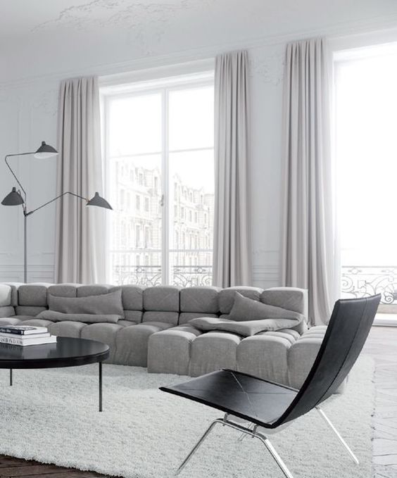 a stunning minimalist space with a statement grey upholstered sof and lilac curtains