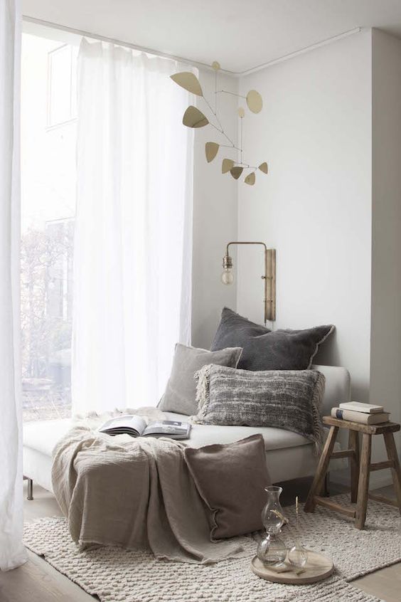 a cozy and natural nook with a daybed, lots of pillows, comfy rugs and a wood stool