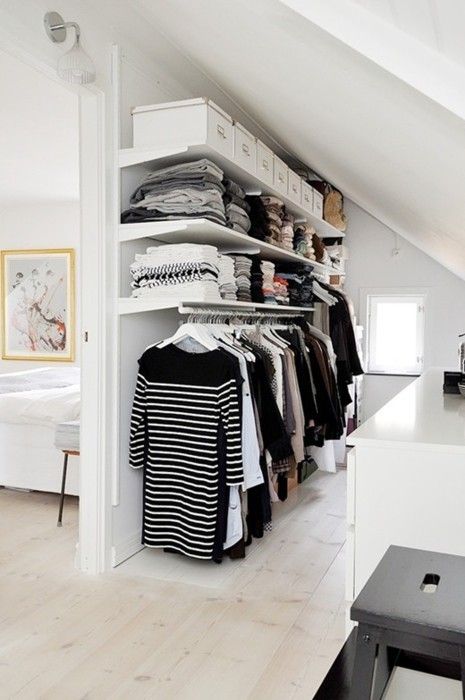 an awkward attic corner is taken by a makeshift closet with open shelving and hangers