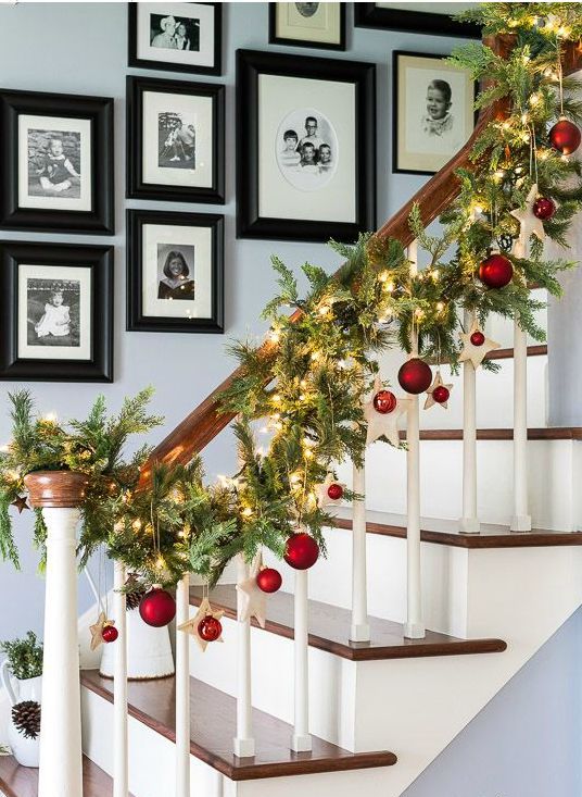 an evergreen garland with lights, stars and red ornaments to line up the stairs