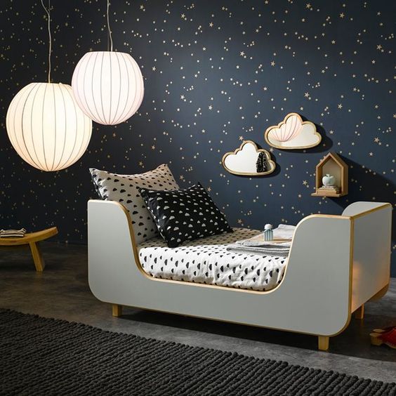A dreamy bedroom with a black starry wall and matching sky inspired bedding