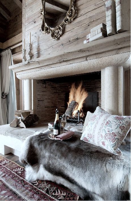 a gorgeous cozy nook at the fireplace, with faux fur and pillows to feel warm and comfy