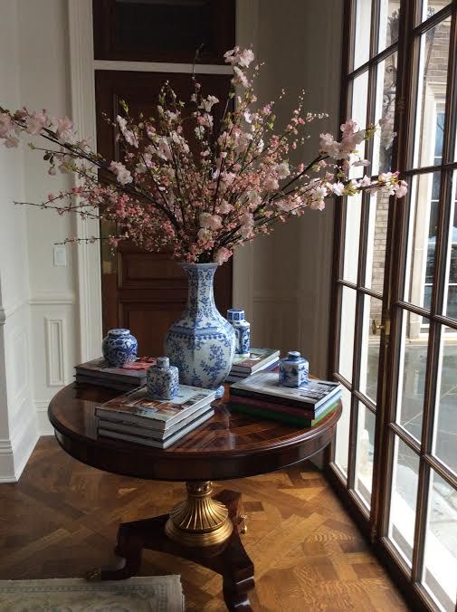 A vintage rich colored wood table serves as a display for books and blue china and makes th einterior refined