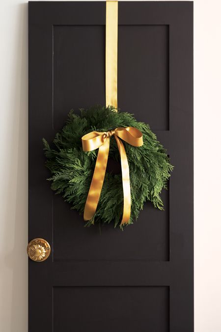 an evergreen wreath with gold ribbon and a bow looks natural and very cute