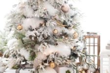 23 a gorgeous flocked Christmas tree with metallic ornaments of various shades and pinecones