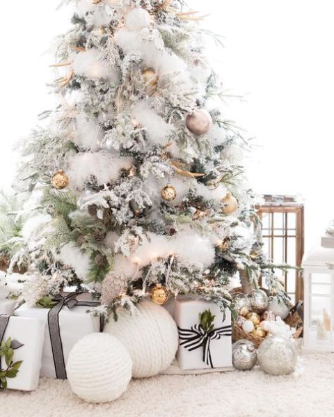 a gorgeous flocked Christmas tree with metallic ornaments of various shades and pinecones