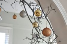 23 decorate an archway with branches and mixed metal ornaments of different sizes and looks