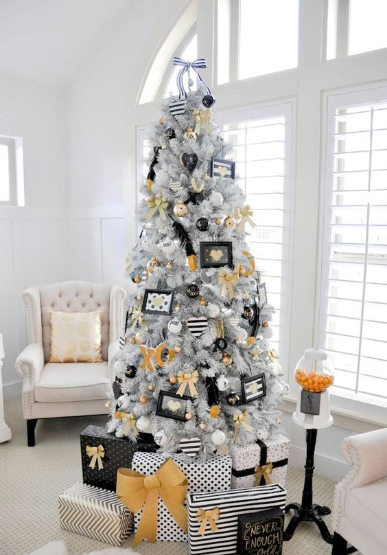 a modern glam Christmas tree with gold, black and white decor and ornaments, letters and feathers