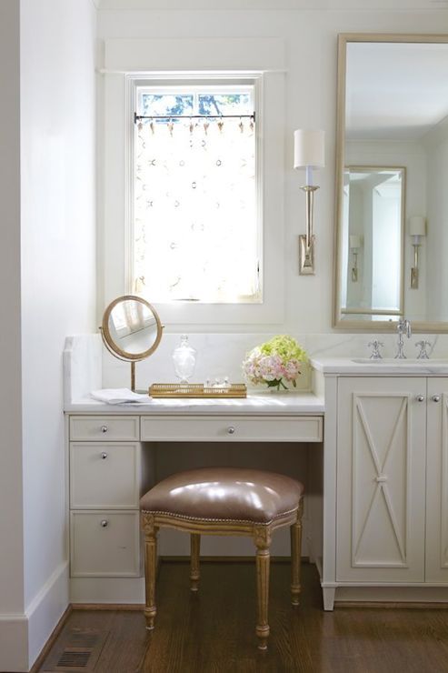 a small beauty nook in the bathroom located next to the window and a lamp over it