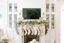 26 neutral stockings, a snowy evergreen garland with copper ornaments and candles for a chic look