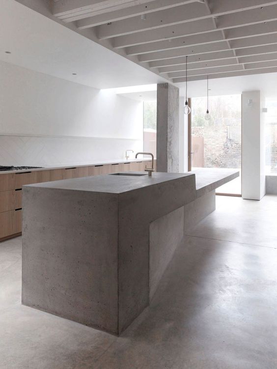 a large sculptural concrete kitchen island and wooden cabinets for a minimal ktichen