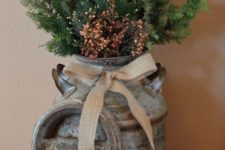 27 a vintage milk churn with a burlap bow, evergreen branches and berries for outdoor decor