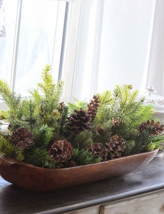 a wooden bread bowl with evergreens and pinecones for a simple rustic display