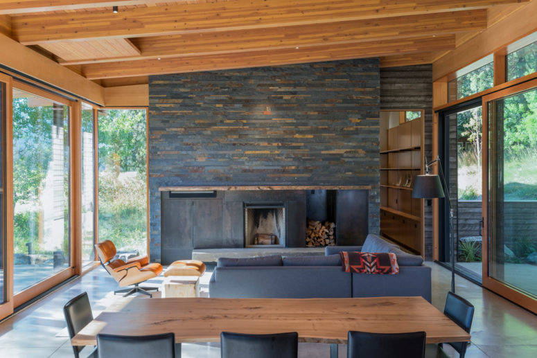 The beautiful living room features a large reclaimed wood clad fireplace and glazed walls from both sides to catch the views