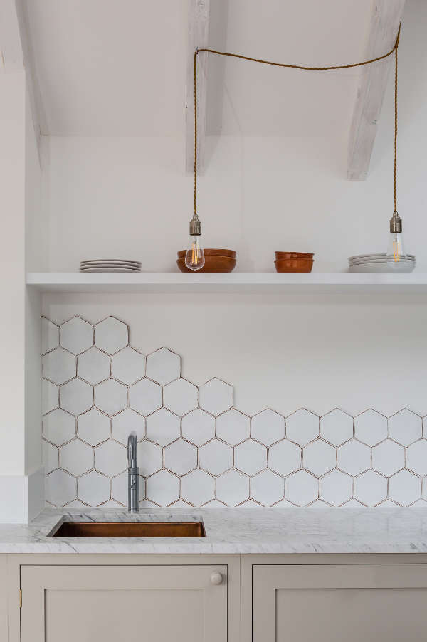 The dove grey cabinets are made more eye catchy with white marble countertops and a white hex tile backsplash