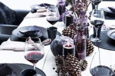 02 a black and purple New Year’s table setting with oversized pinecones, purple candles and black chargers and plates