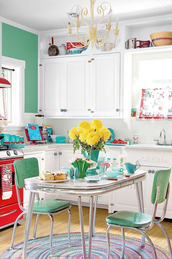 a bold green accent wall, matching chairs, a red cooker and turquoise touches ehre and there