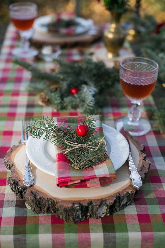 a plaid tablecloth, plaid napkins and evergreens with berries for a cozy rustic tablescape