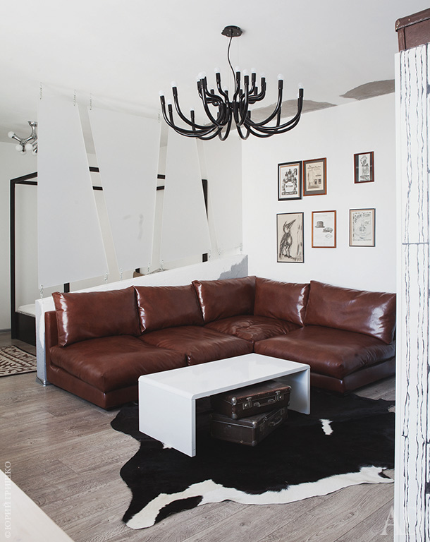 A faux animal skin rug adds coziness, and large black chandelier is inspired by antlers