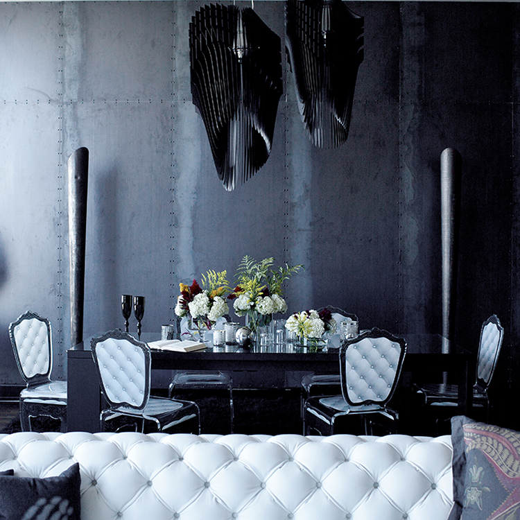 The dining space is defined with black sculptural chandeliers and metal pillars