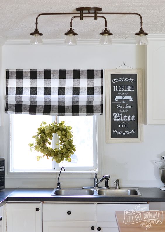 a buffalo check roman shade, a greenery wreath and a chalkboard sign for a cozy barn-styled kitchen
