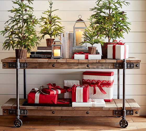 evergreen trees in baskets and gifts and candle lanterns for a festive feel
