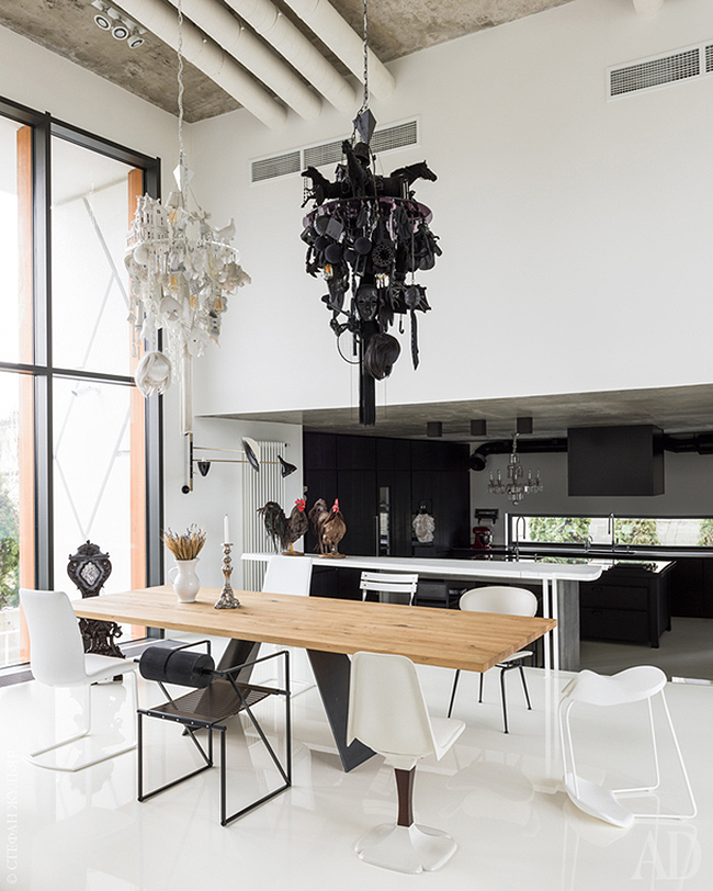 The dining space is done in black and white, with mismatching chairs and unique chandeliers