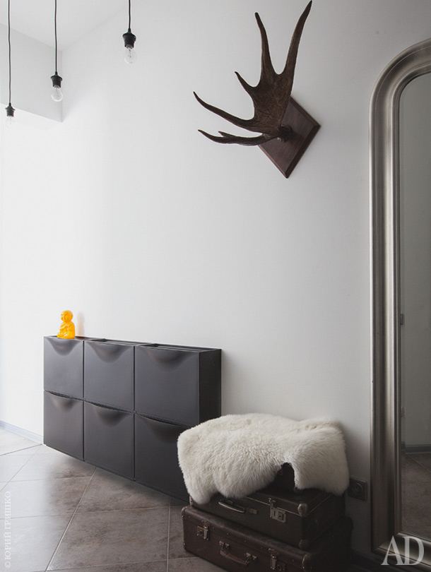 The entryway is done with vintage suitcases for storage, antlers and a black wall-mounted storage piece
