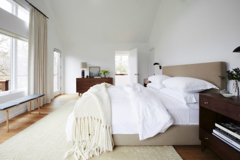The master bedroom is decorated in neutral shades, with much natural light and several dark-colored wooden pieces