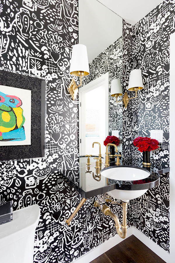 The mudroom features black and white graphic wallpaper, a colorful artwork and elegant brass touches