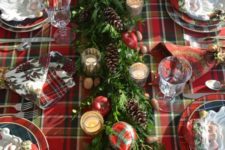 05 a plaid tablecloth, a greenery table runner with pinecones, apples, plaid ornaments and mercury glass candle holders