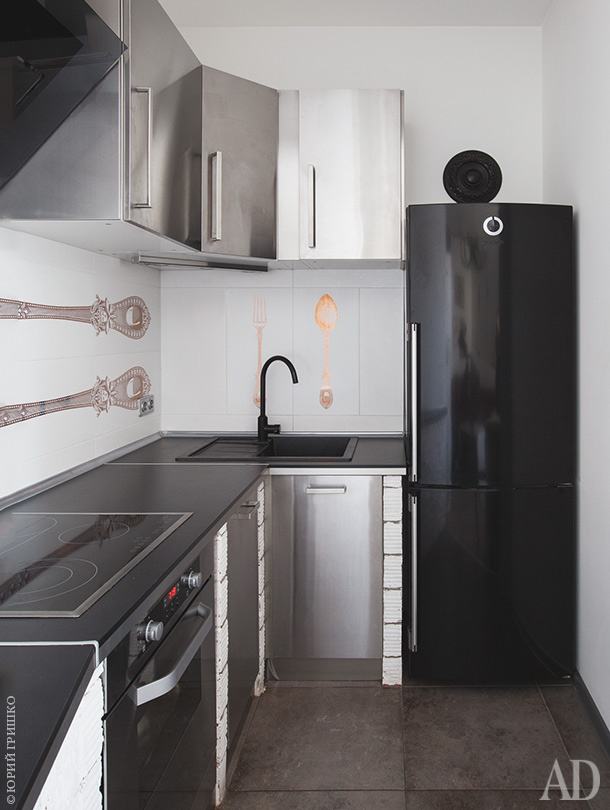 The small kitchen is done with stainless steel cabinets, a black fridge and a tile backsplash