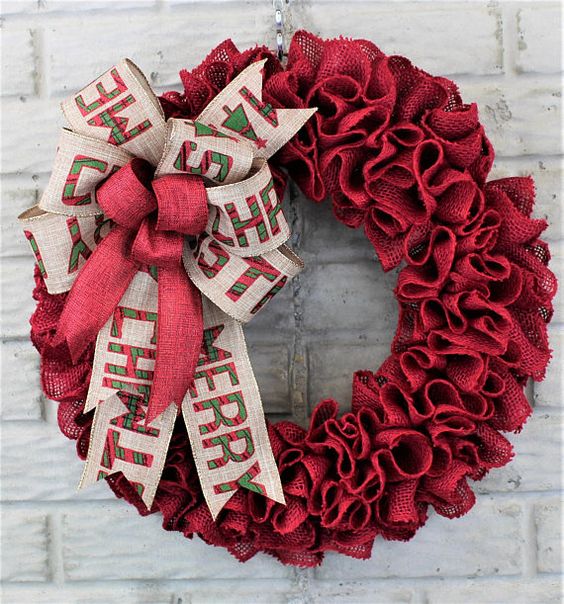 A red burlap wreath with large bows with letters looks bold and festive