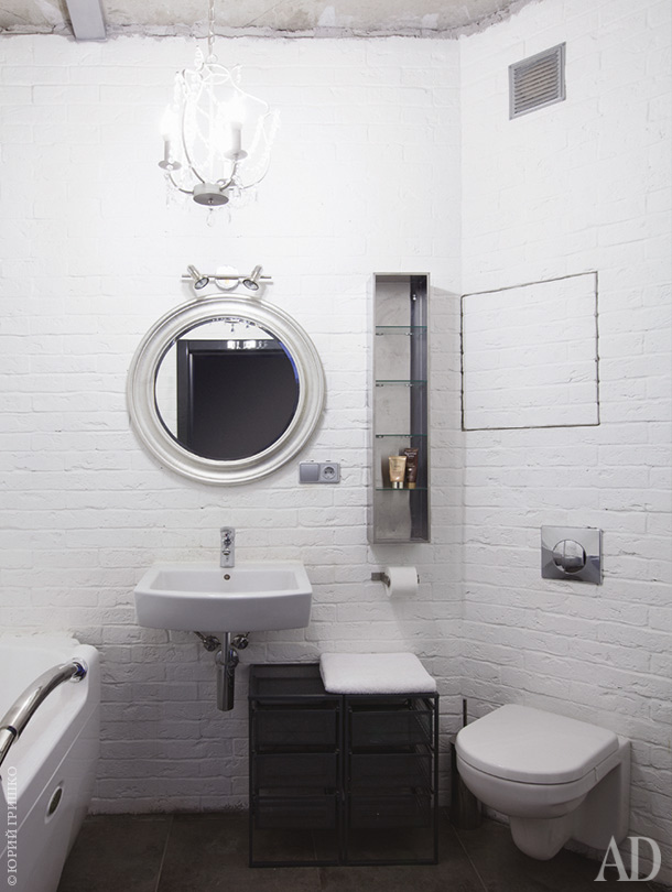 The bathroom is done with faux brick walls, some white appliances and a glass shelf on the wall