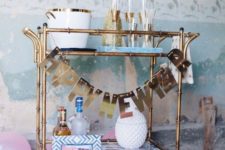 07 a brass bar cart with a shiny letter garland is all you need for party decor